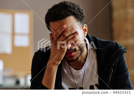 Young depressed man touching face while suffering from post traumatic syndrome Young depressed man touching face while suffering from post traumatic syndrome 94935415