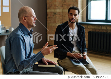 Confident mature male psychotherapist explaining something to patients 94935422