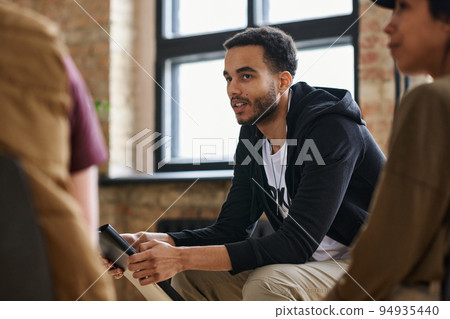 Young man with post traumatic syndrome in casualwear sitting among others 94935440
