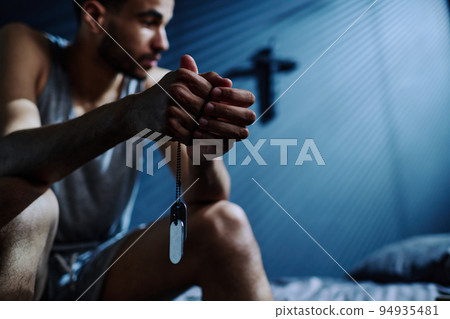 Hands of young insomniac man holding silver chain with medallions 94935481