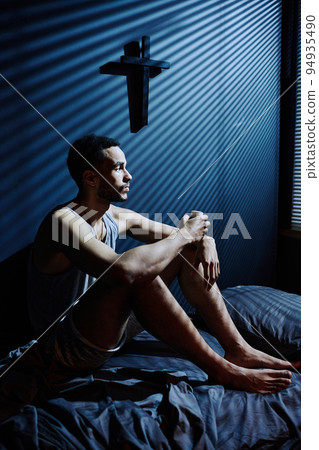 Young depressed man sitting on bed while staying awake till morning 94935490