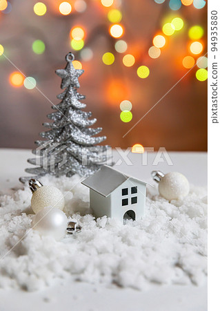 Abstract Advent Christmas Background. Toy model house and winter decorations ornaments on background with snow and defocused garland lights. Christmas with family at home concept 94935880