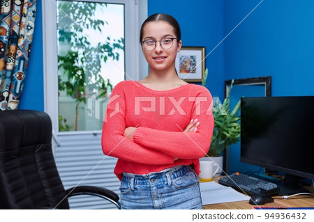 Portrait of teenage female student at home near desk with computer Portrait of teenage female student at home near desk with computer 94936432