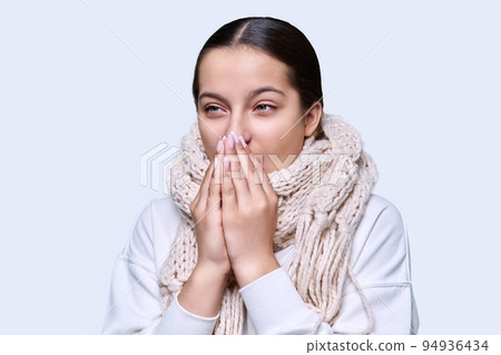 Winter portrait of young female in sweater scarf, on light studio background Winter portrait of young female in sweater scarf, on light studio background 94936434