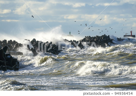 Big waves created during stormy weather crash against the breakwater concrete tetrapods 94936454