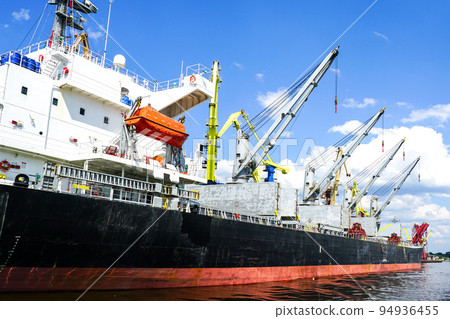 Large bulk cargo ship with open holds in the port cargo terminal, blue sky background 94936455