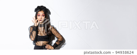 Pretty asian girl in witch costume making promise, seal lips and keep secret, zip mouth, censored information, standing over white background in halloween outfit Pretty asian girl in witch costume making promise, seal lips and keep secret, zip mouth, censored information, standing over white background in halloween outfit 94938624