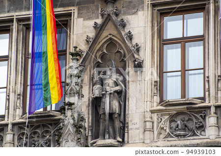 Close-Up rainbow gay pride flag outside on a street. Symbol of the Lesbian Bisexual Transgender LGBT community waving in wind against cloudy sky. Social movement for freedom and equliaty. Copy Space  94939103