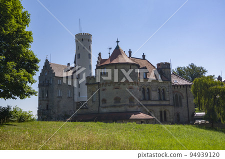 Photo of lichtenstein castle or Schloss on forested rock cliff in Swabian Alps in summer. Seasonal panorama of romantic fairytale palace in Gothic revival style over sky. European famous landmark Photo of lichtenstein castle or Schloss on forested rock cliff in Swabian Alps in summer. Seasonal panorama of romantic fairytale palace in Gothic revival style over sky. European famous landmark 94939120