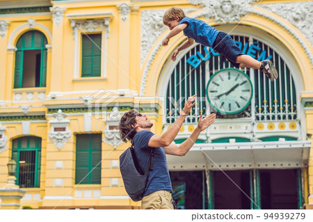 Father and son on background Saigon Central Post Office on blue sky background in Ho Chi Minh, Vietnam. The inscription on the Vietnamese post office Father and son on background Saigon Central Post Office on blue sky background in Ho Chi Minh, Vietnam. The inscription on the Vietnamese post office 94939279