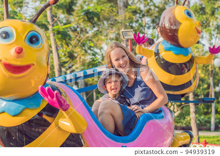 Mom and son having fun at an amusement park Mom and son having fun at an amusement park 94939319