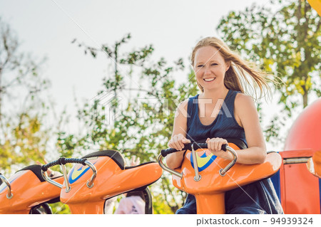 Beautiful, young woman having fun at an amusement park Beautiful, young woman having fun at an amusement park 94939324