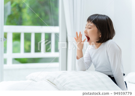 sleep deprived girl yawning in bed sleep deprived girl yawning in bed 94939779
