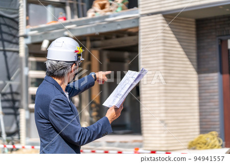 將設計圖紙與施工現場進行比較的施工主管白髮鬍鬚 94941557