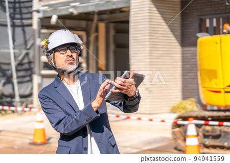 將設計圖紙與施工現場進行比較的施工主管白髮鬍鬚 94941559