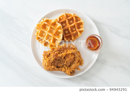 fried chicken waffle with honey or maple syrup 94943291