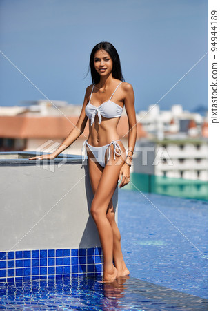 Young asian sexy girl in a white bikini posing at hotel territory swimming pool Young asian sexy girl in a white bikini posing at hotel territory swimming pool 94944189
