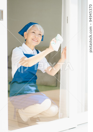 Housekeeper senior woman cleaning windows 94945370