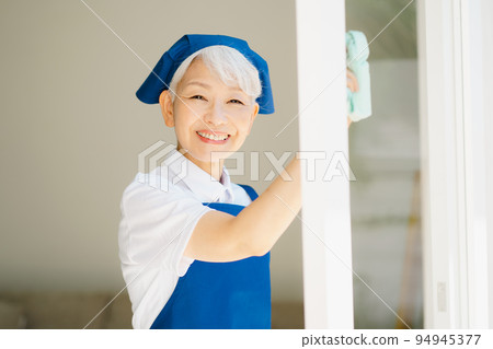Housekeeper senior woman cleaning windows 94945377