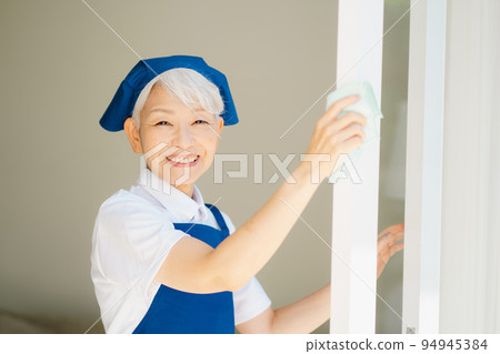 Housekeeper senior woman cleaning windows 94945384