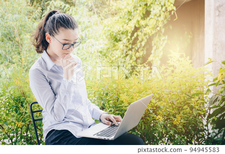 Portrait of young mixed race businesswoman using her laptop and thinking something. Portrait of young mixed race businesswoman using her laptop and thinking something. 94945583