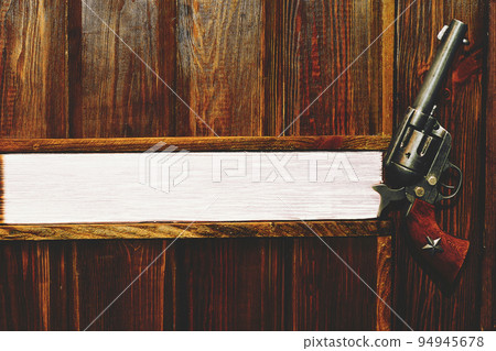 Cowboy gun revolver on a light brown wooden wall . Space for text. Boss's office 94945678