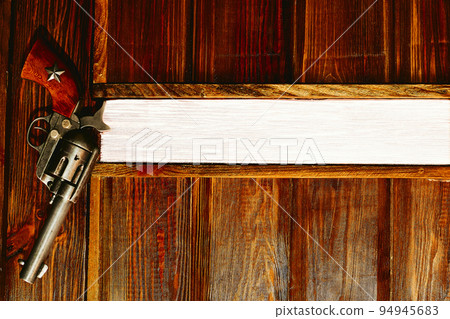 Cowboy gun revolver hanging on a wooden wall with space for text. Boss's office Cowboy gun revolver hanging on a wooden wall with space for text. Boss's office 94945683
