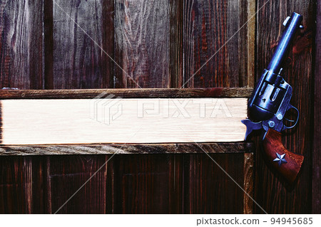 Cowboy gun revolver on a dark brown wooden wall . Space for text. Boss's office 94945685