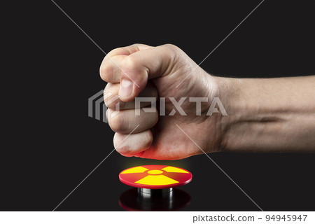 The hand presses the big red button. The concept of the threat of nuclear war. A threat to the world with a nuclear suitcase and a bomb. The hand presses the rocket launch button. The hand presses the big red button. The concept of the threat of nuclear war. A threat to the world with a nuclear suitcase and a bomb. The hand presses the rocket launch button. 94945947