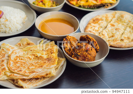Assorted indian food on dark wooden background. Dishes and appetizers of indian cuisine. Curry, butter chicken, rice, lentils, paneer, samosa, naan, chutney, spices. Bowls and plates with indian food Assorted indian food on dark wooden background. Dishes and appetizers of indian cuisine. Curry, butter chicken, rice, lentils, paneer, samosa, naan, chutney, spices. Bowls and plates with indian food 94947111