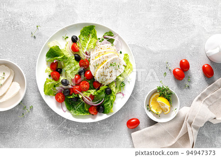 Salad with mozzarella cheese, cherry tomato, olives and romain lettuce, top view Salad with mozzarella cheese, cherry tomato, olives and romain lettuce, top view 94947373