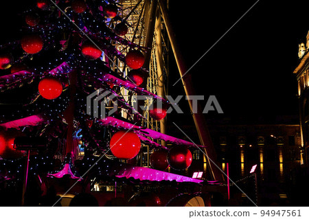 Christmas tree with red balls, pink wings. Glowing ferris wheel,night house Christmas tree with red balls, pink wings. Glowing ferris wheel,night house 94947561