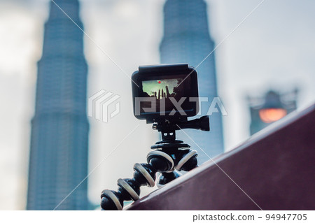 Action camera on a tripod records a video of the time-lapse of a big city 94947705
