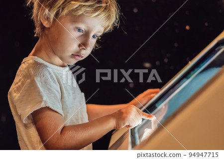 The boy uses the touch screen in the dark The boy uses the touch screen in the dark 94947715