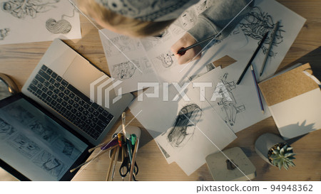 Young woman artist draws pencil sketches works on storyboard of a comic top view Young woman artist draws pencil sketches works on storyboard of a comic top view 94948362
