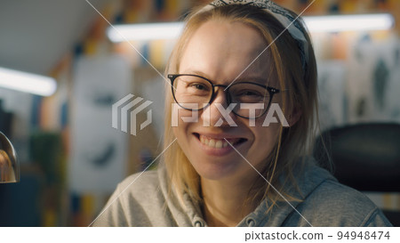 Blonde woman face closeup with black framed glasses looks at camera and smiles Blonde woman face closeup with black framed glasses looks at camera and smiles 94948474