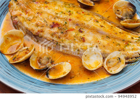 Delicious cooked clams and halibut in a buttery sauce on a plate. Delicious cooked clams and halibut in a buttery sauce on a plate. 94948952