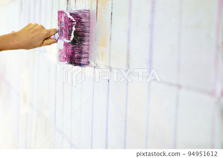 Brush painting dyeing surface of white wall with pink magenta purple paint 94951612