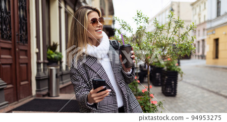 woman Tourist walks around the city sightseeing with a cup of coffee and a mobile phone woman Tourist walks around the city sightseeing with a cup of coffee and a mobile phone 94953275
