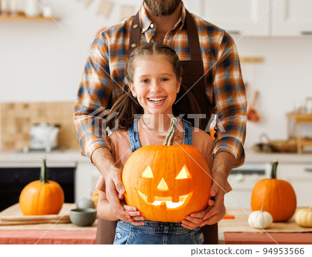 Girl and dad making Jack-o-Lantern together at home, carving Halloween pumpkin 94953566