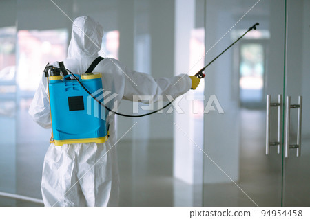 Disinfecting of office to prevent COVID-19, Man in protective hazmat suit with with spray chemicals. Disinfecting of office to prevent COVID-19, Man in protective hazmat suit with with spray chemicals. 94954458