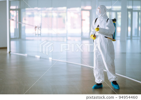 Disinfecting of office to prevent COVID-19, Man in protective hazmat suit with with spray chemicals. 94954460