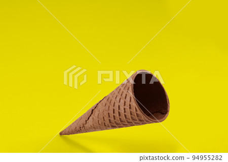 Empty wafer cone for ice cream against yellow background. Concept of food, treats. Mockup, template for your advertising and design. Close up 94955282