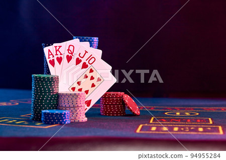 Winning combination in poker standing leaning on multicolored chips piles on blue cover of playing table. Black background. Casino concept. Close-up. Winning combination in poker standing leaning on multicolored chips piles on blue cover of playing table. Black background. Casino concept. Close-up. 94955284
