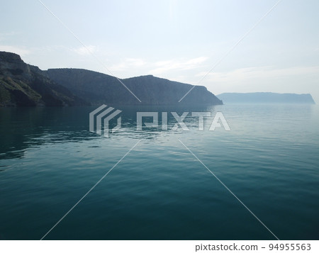 Aerial view from above on calm azure sea and volcanic rocky shores. Small waves on water surface in motion blur. Nature summer ocean sea beach background. Nobody. Holiday, vacation and travel concept Aerial view from above on calm azure sea and volcanic rocky shores. Small waves on water surface in motion blur. Nature summer ocean sea beach background. Nobody. Holiday, vacation and travel concept 94955563