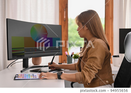 Young creative woman using graphic tablet and professional computer working for design project at home office Young creative woman using graphic tablet and professional computer working for design project at home office 94955656