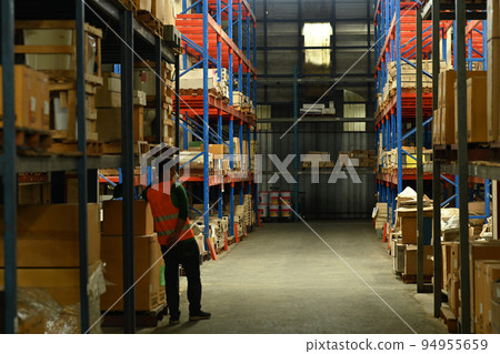 Warehouse workers wearing safety hardhat working on retail warehouse full of packed boxes and goods 94955659