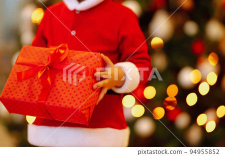 Little boy in santa costume with christmas gift. Happy child holding red present box. New Year. Little boy in santa costume with christmas gift. Happy child holding red present box. New Year. 94955852