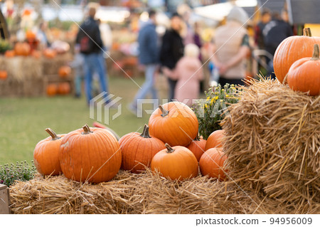Pumpkins on straw bales against the background of people at an agricultural fair 94956009