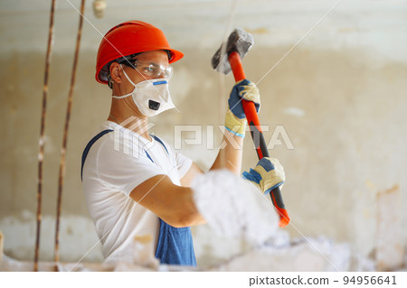 Young male builder in hard hat holding tools. Apartment repair and renovation concept. 94956641